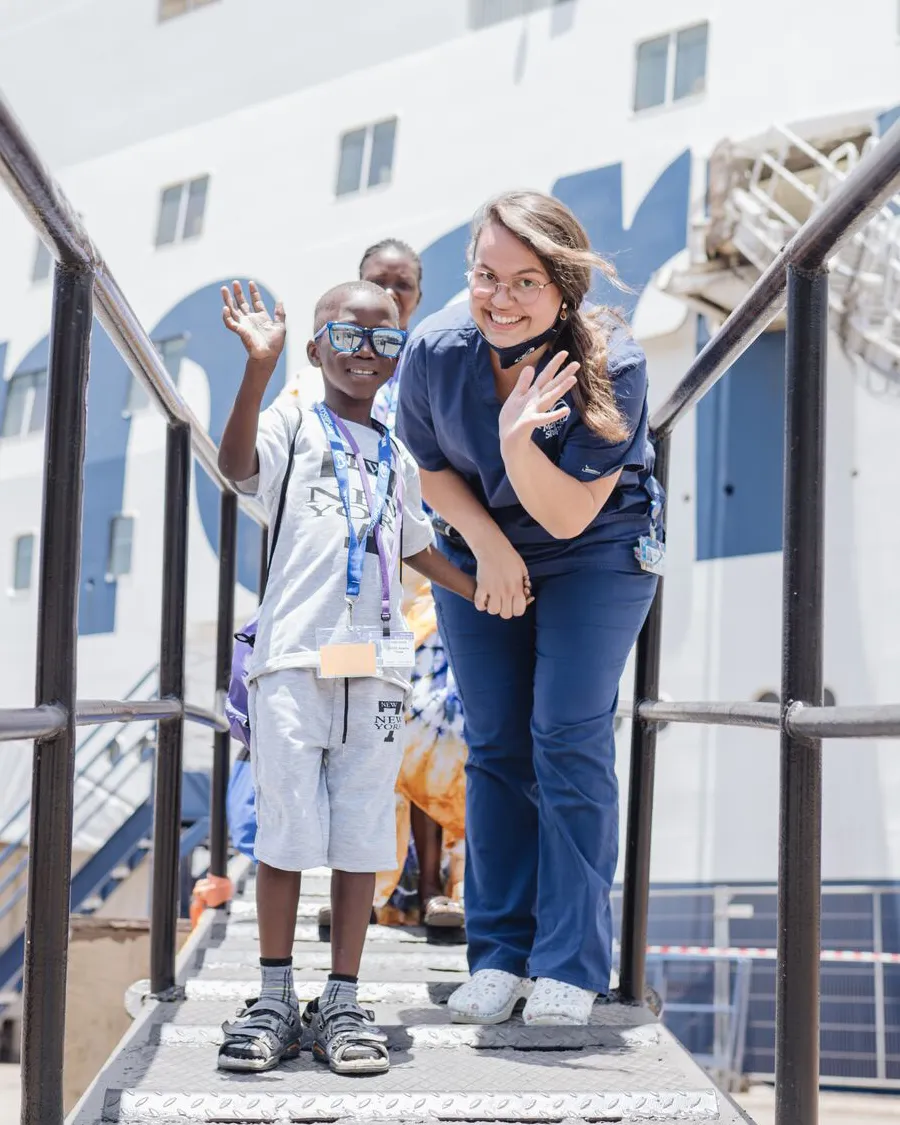 Voluntaria y un niño saludando desde el barco